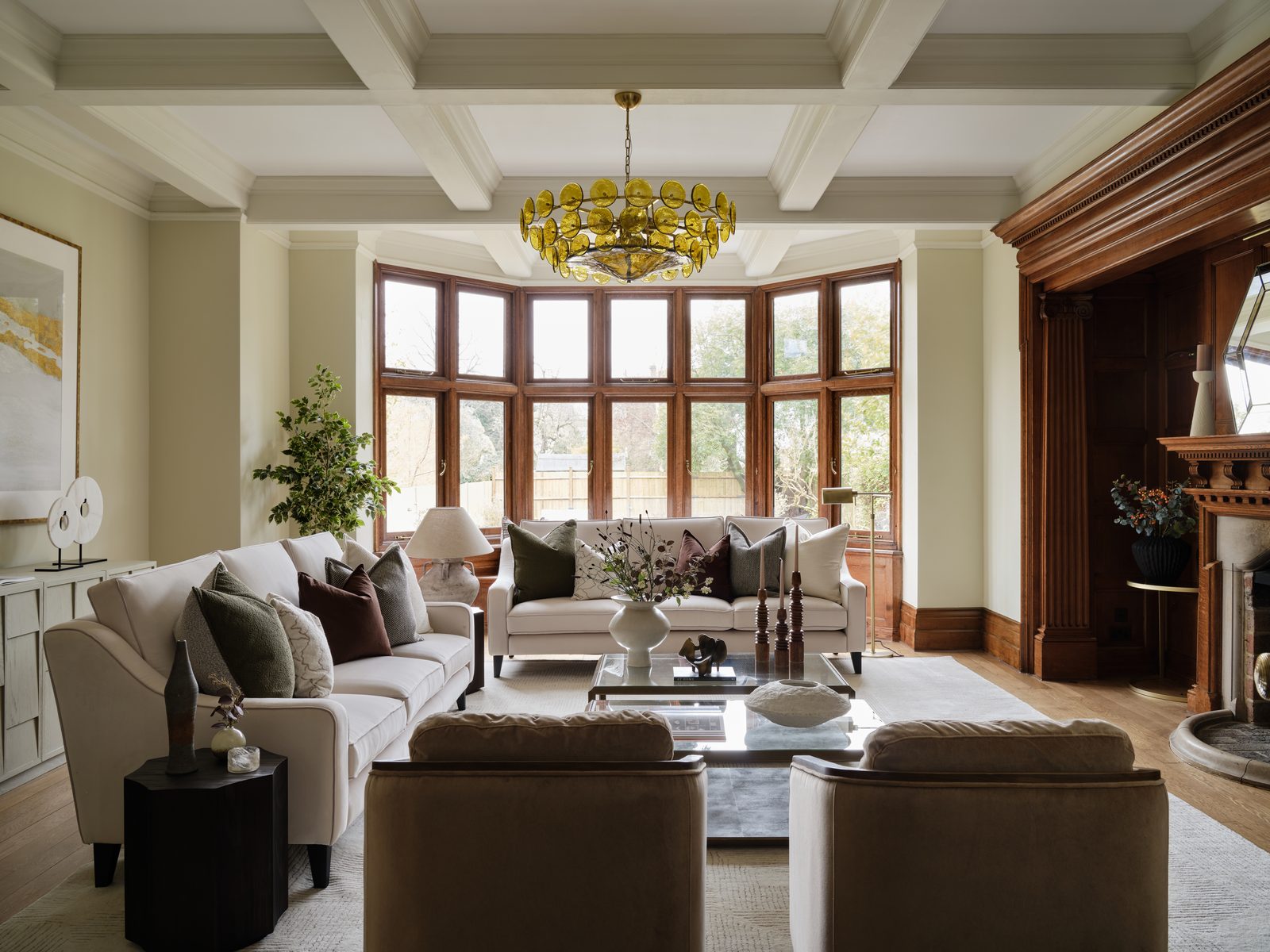 A staged reception room at Southside Common with a panelled bay window, coffered ceiling and a yellow glass chandelier
